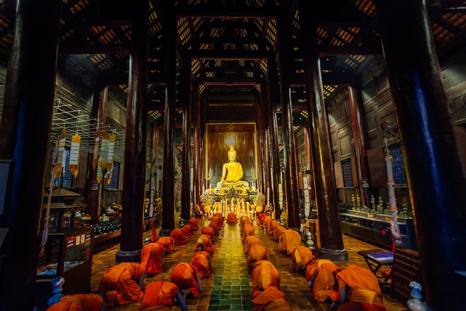 Temple interior with a golden Buddha and monks in saffron robes